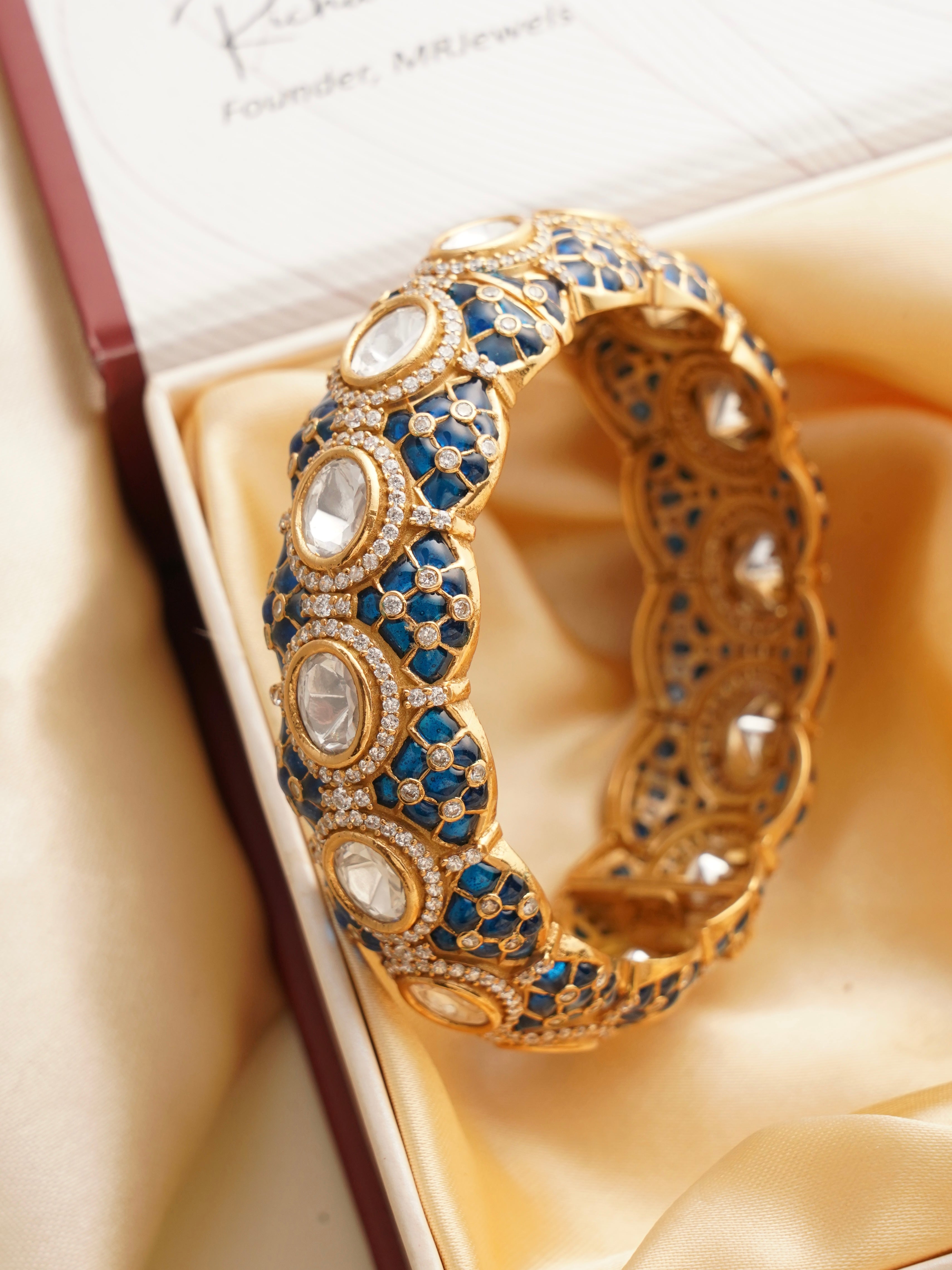 Overhead view of ruby-studded bangle with kundan accents and elegant gold tone